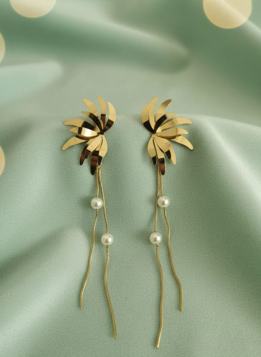 Gold leaf earrings with pearl accents on a green fabric background