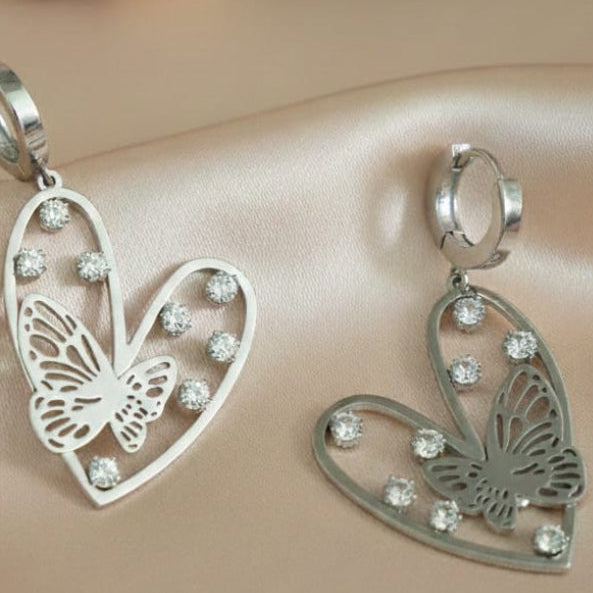 Silver-Toned Heart And Butterfly Drop Huggie Earrings With Rhinestone Accents.