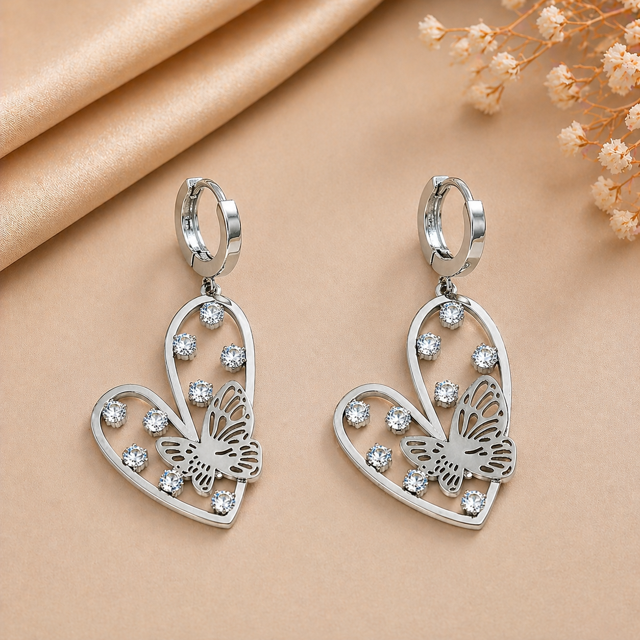 Silver-Toned Heart And Butterfly Drop Huggie Earrings With Rhinestone Accents.