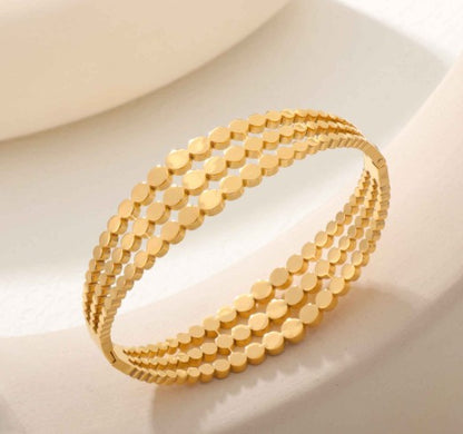 Gold plated Stainless Steel three-layered bangle bracelet featuring a cutout disc pattern